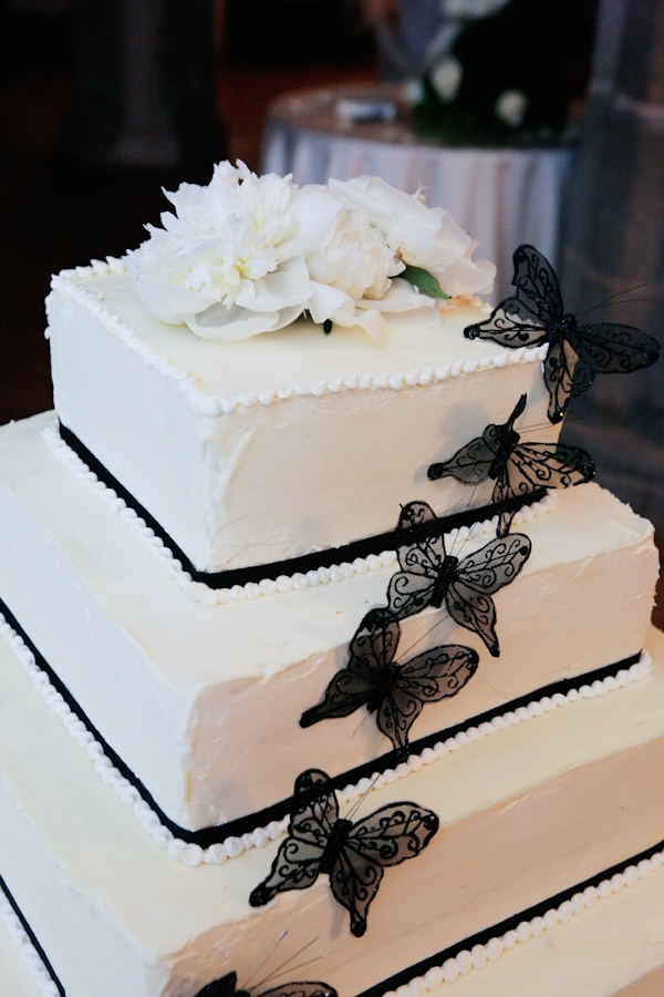 white square four tier wedding cake with black borders and black butterfly decor with a white floral top - photo by Italian wedding photographer JoAnne Dunn